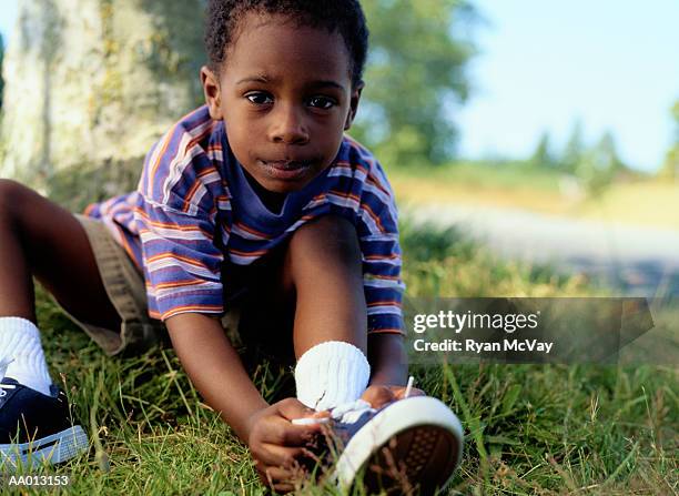 boy tying his tennis shoe - boy tying shoes stock-fotos und bilder