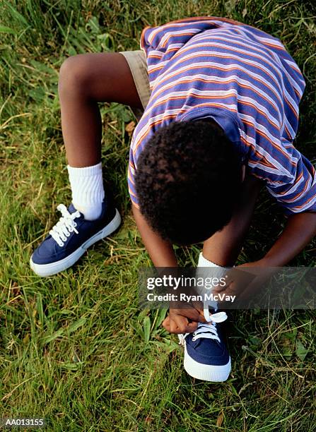 boy tying his tennis shoe - boy tying shoes stock-fotos und bilder