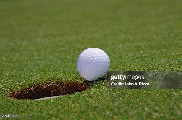 close-up of a golf ball beside a hole - off target stockfoto's en -beelden