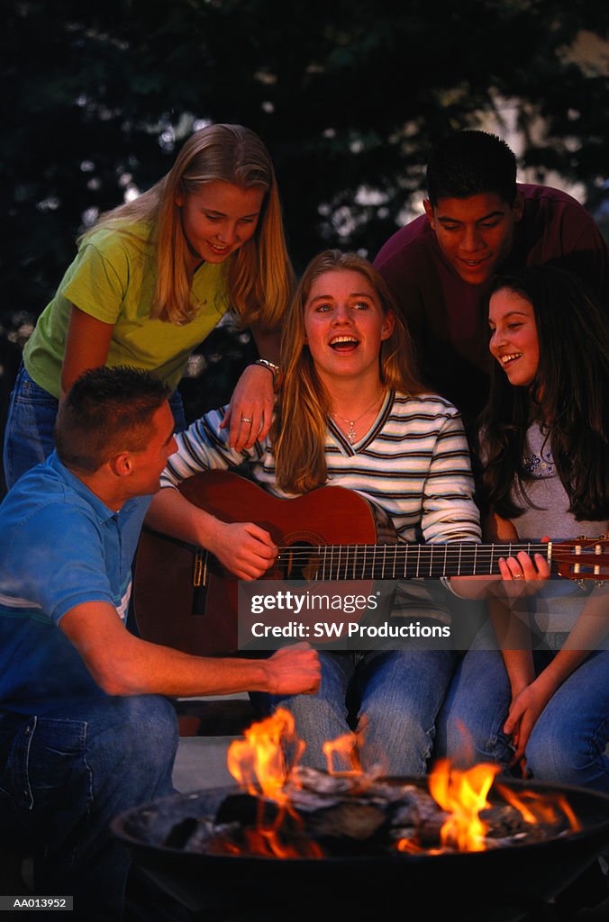 Teens Singing Around a Campfire