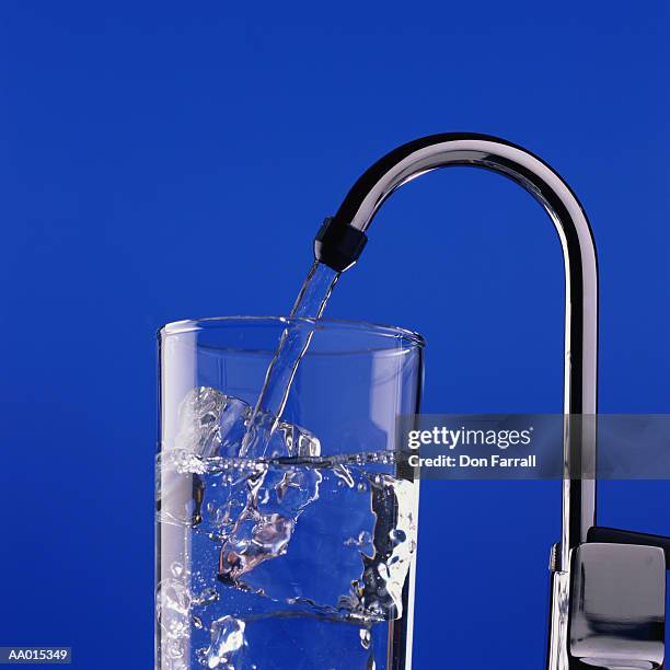 glass of ice under a purified water faucet - purified water stockfoto's en -beelden