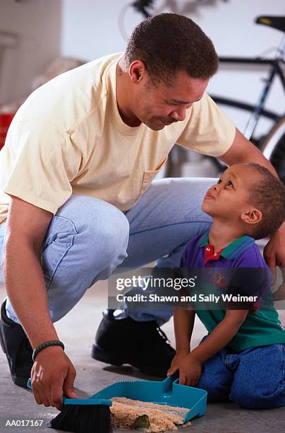 father and son cleaning sawdust mess - cleaning sawdust stock pictures, royalty-free photos & images