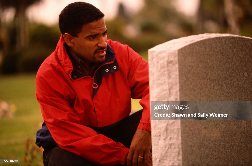 Pensive Man Looking at a Tombstone in a Cemetery