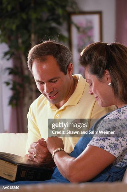 religious couple praying together at home - godsdienstvrijheid stockfoto's en -beelden