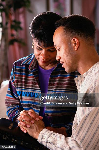 religious couple praying together at home - godsdienstvrijheid stockfoto's en -beelden
