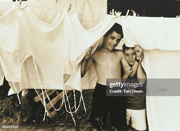 boys playing beneath a clothesline - sépia photos et images de collection