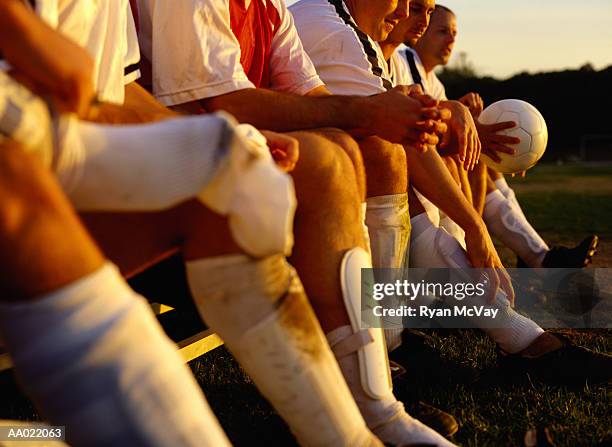 soccer team sitting on a bench - side lines stockfoto's en -beelden