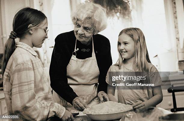 great-grandmother teaches girls to bake - great granddaughter fotografías e imágenes de stock