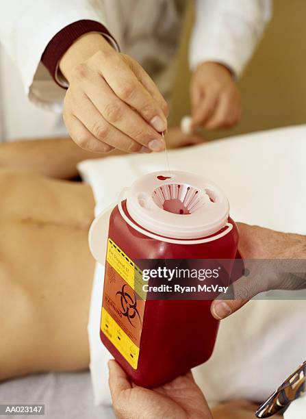 putting a needle into a biohazard container - disposal container stock pictures, royalty-free photos & images