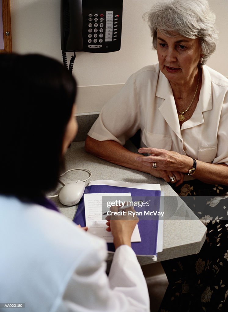 Doctor writing prescription for mature female patient