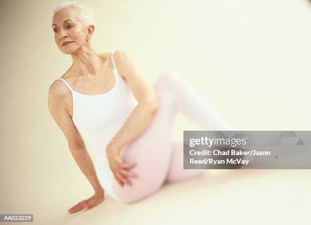 elderly woman in a yoga pose - ardha matsyendrasana stock-fotos und bilder