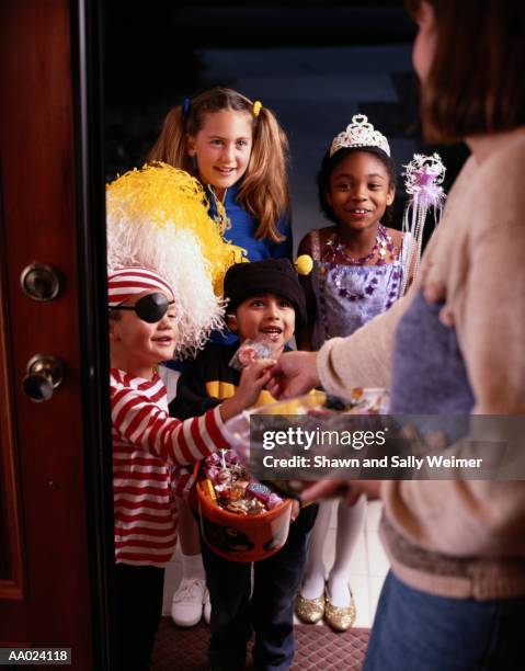 woman giving candy to children on halloween - princess pirates stock pictures, royalty-free photos & images