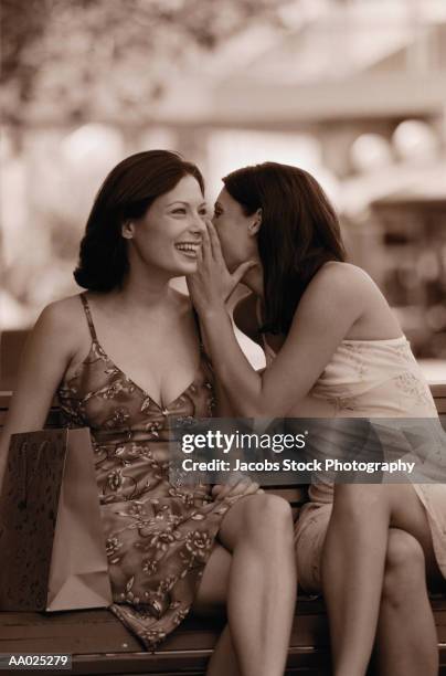 two women whispering - two toned dress stockfoto's en -beelden