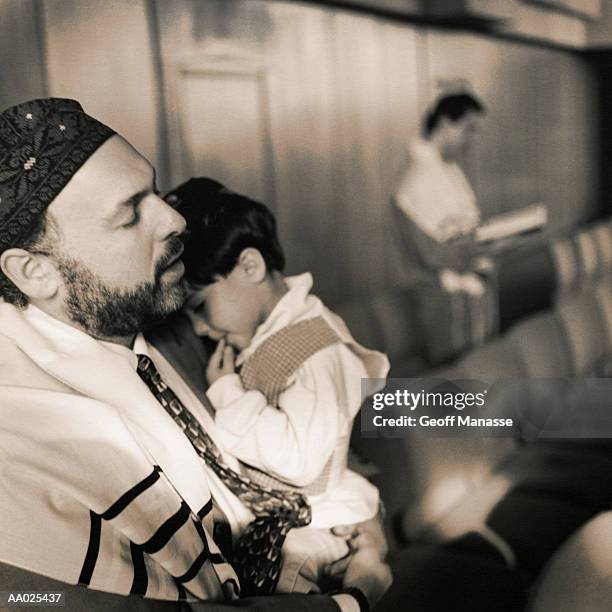 jewish father and son praying at synagogue - religieuze muziek stockfoto's en -beelden