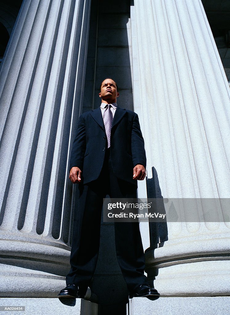 Businessman Standing Between Columns