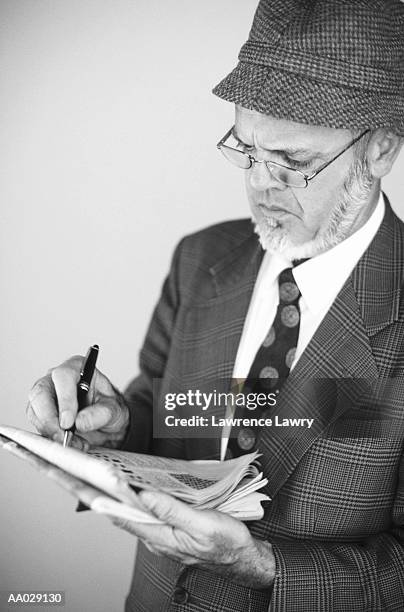mature man doing crossword puzzle - crossword stock pictures, royalty-free photos & images