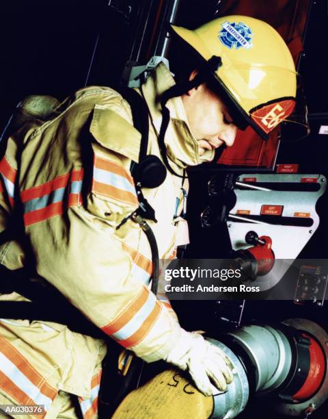 firefighter connecting hose to truck, profile - emergency services equipment stock pictures, royalty-free photos & images