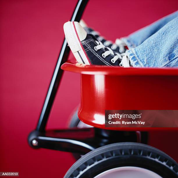 boy sitting in a red wagon - toy wagon stock pictures, royalty-free photos & images