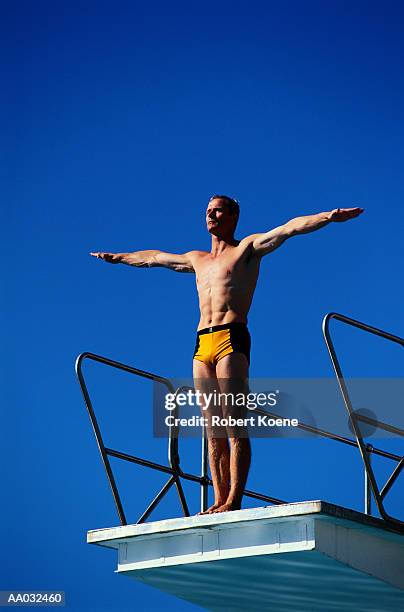 diver performing a dive - young men in speedos stock-fotos und bilder