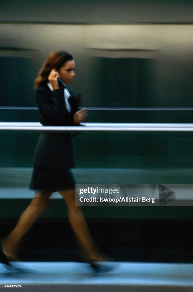 Businesswoman walking, using mobile phone (blurred motion)
