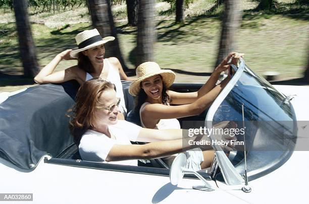 three friends riding in a convertible - alleen jonge vrouwen stockfoto's en -beelden