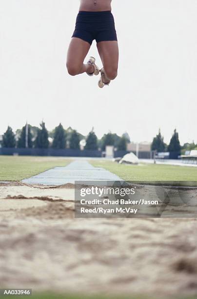 young woman performing the long jump - evento de prueba de campo feminino fotografías e imágenes de stock