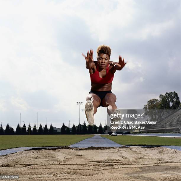 young woman performing the long jump - womens field event stock pictures, royalty-free photos & images