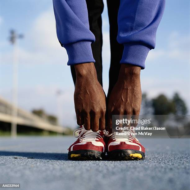 male athlete stretching on track - black male feet fotografías e imágenes de stock