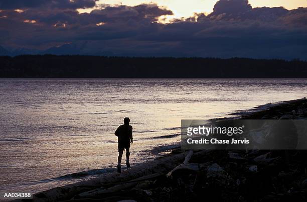 runner jogs along beach at dusk - discovery park stock pictures, royalty-free photos & images