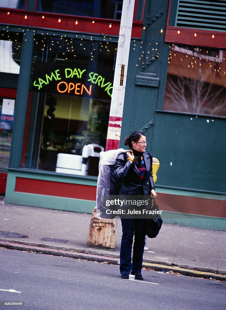 Young Woman Crossing Street With Dry Cleaning