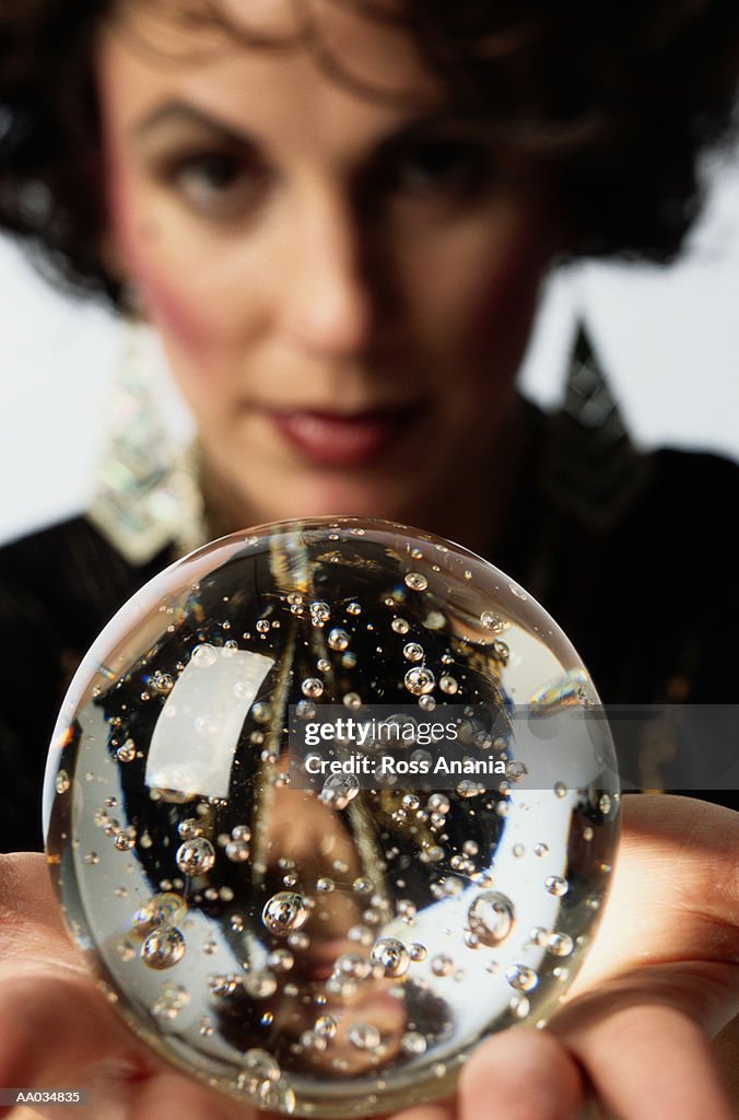 Woman holding crystal ball, close-up (focus on ball)