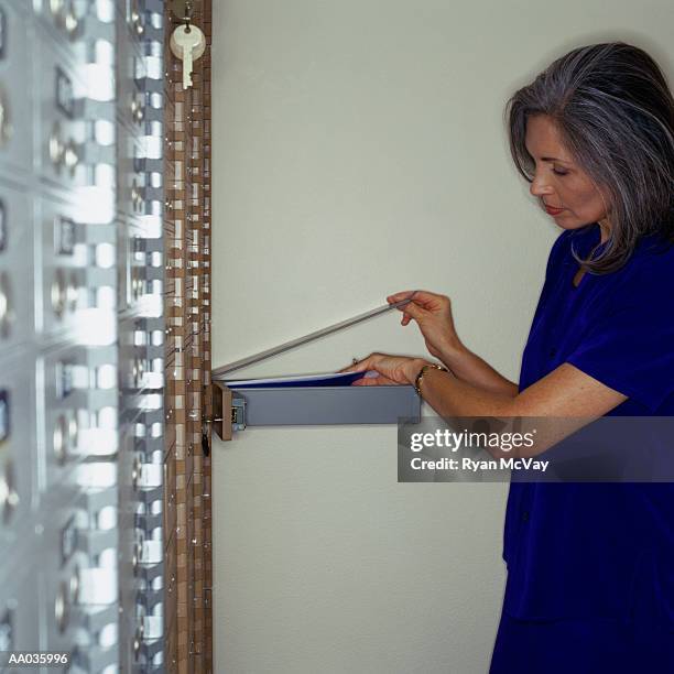 woman getting into safety deposit box - safety deposit box stock pictures, royalty-free photos & images