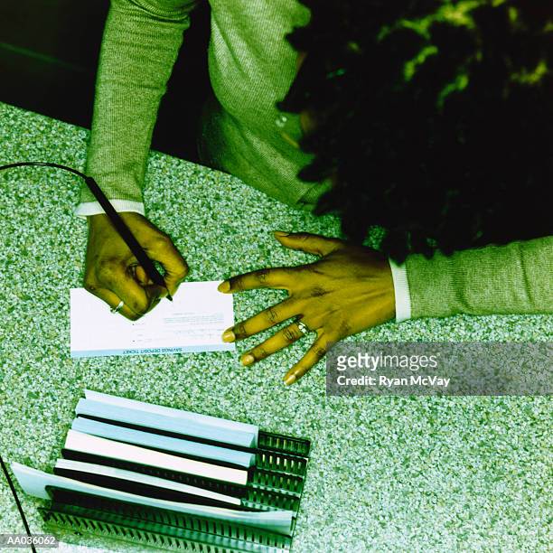 woman writing on a bank deposit slip - bank deposit slip fotografías e imágenes de stock