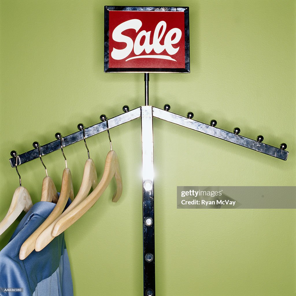 Clothes and wooden hangers hanging on sale rack, close-up