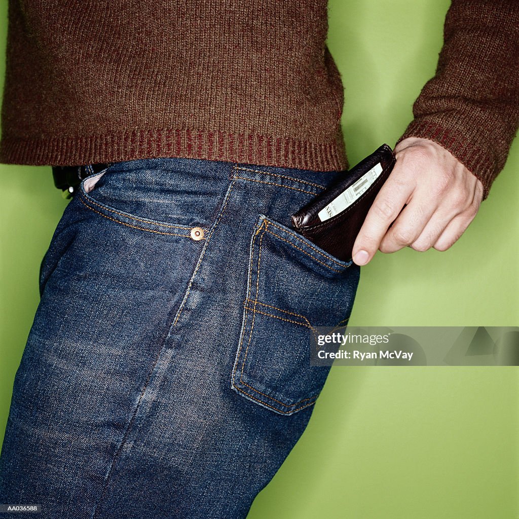Young man putting wallet in back pocket, mid section, side view
