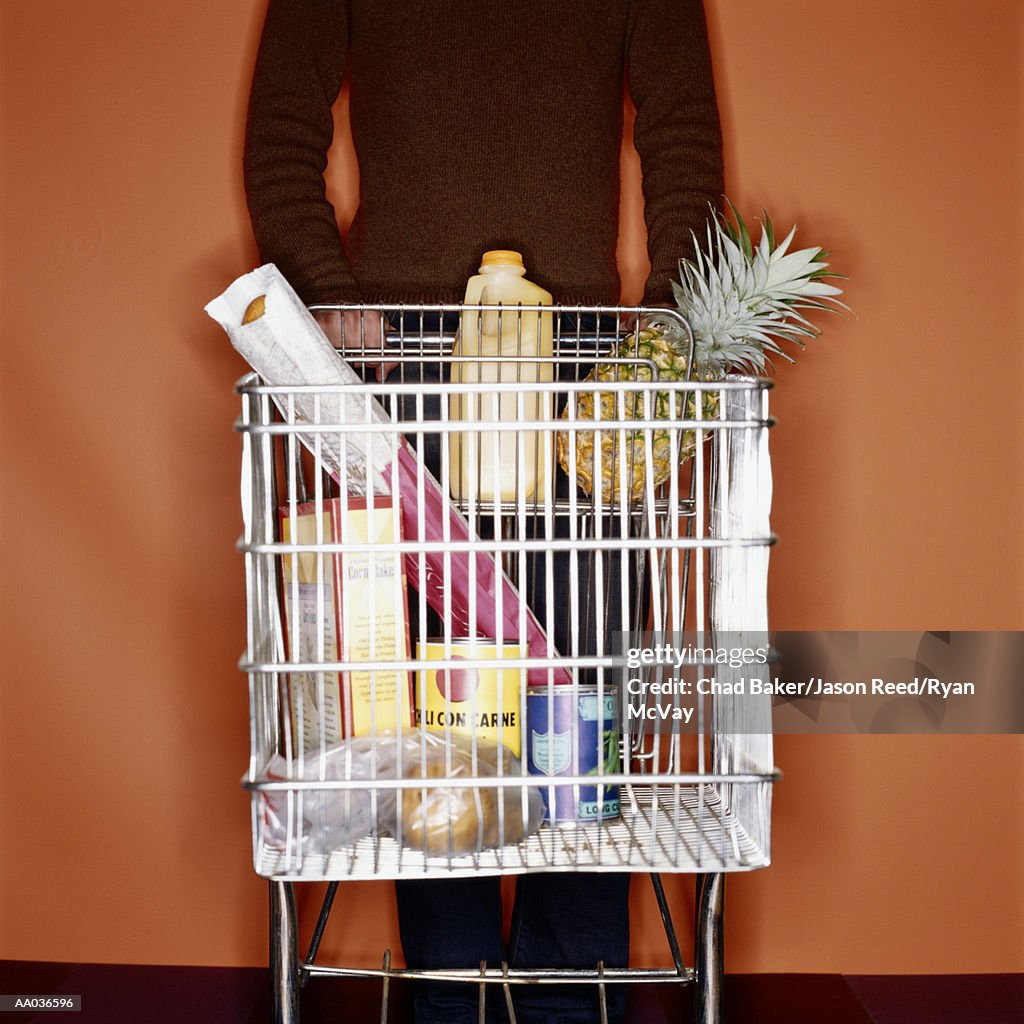 Young man pushing shopping cart, mid section