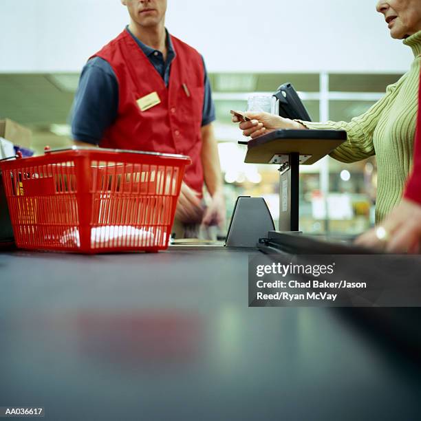 woman in supermarket using credit card, mid section - caisse photos et images de collection