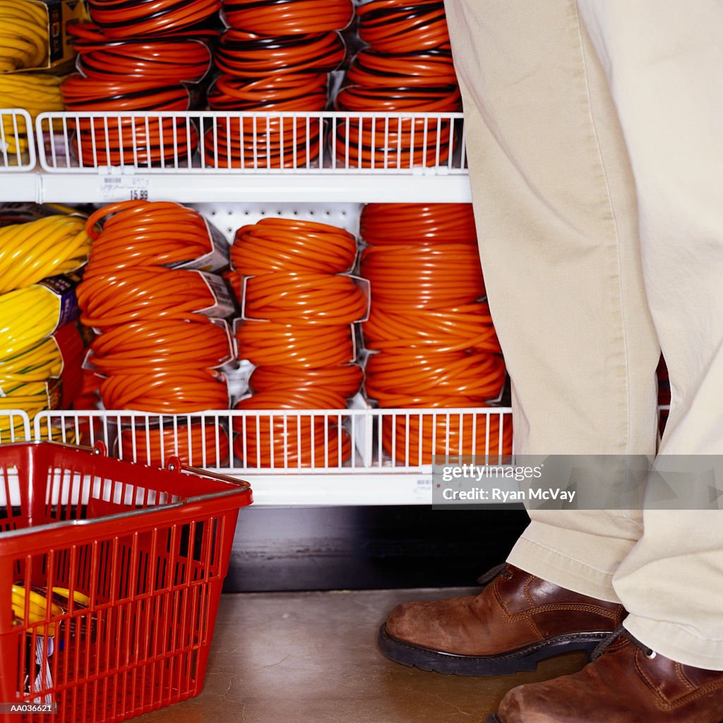 Man shopping in hardware store for extension cord, low section