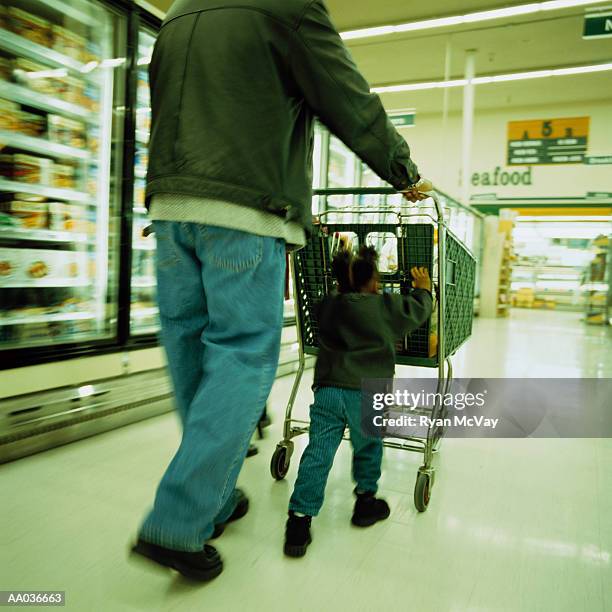 father and toddler (21-24 months) pushing shopping cart in supermarket - processo cruzado imagens e fotografias de stock