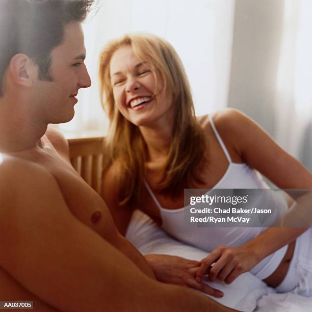 young couple lying in bed woman laughing - reed bed stock pictures, royalty-free photos & images