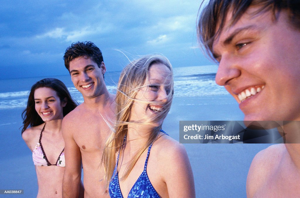 Two teenage couples (16-18) at beach smiling