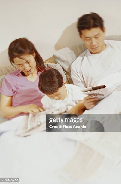 family reading in bed - bedtime stories stock-fotos und bilder