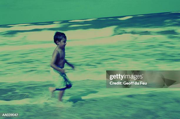 boy (6-8) running on beach, side view (blurred motion, green tone) - du stock pictures, royalty-free photos & images