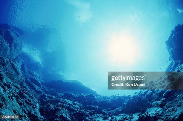 sun shining on rock face, scuba diver in distance, underwater view - okinawa islands stock pictures, royalty-free photos & images