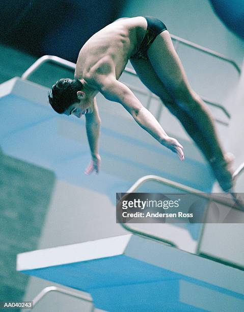 teenage boy (16-18) diving off of platform (cross-processed) - speedo boy stock pictures, royalty-free photos & images