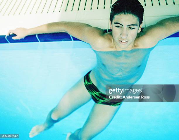 teenage boy (15-17) resting on the side of pool, elevated view - speedo boy stock pictures, royalty-free photos & images