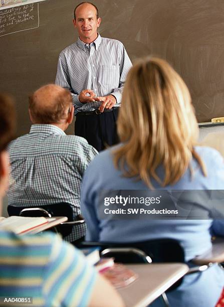 male teacher instructing adult students - avondschool stockfoto's en -beelden