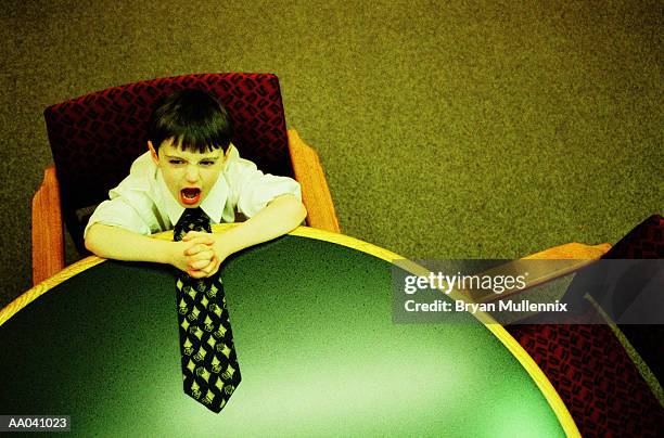boy (4-6) siting at conference table, elevated view (cross-processed) - adult imitation stock pictures, royalty-free photos & images