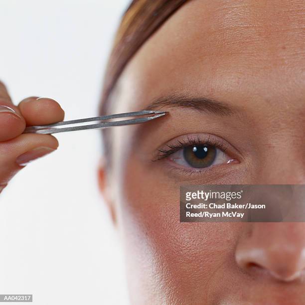 young woman plucking eyebrows - eyebrow tweezers imagens e fotografias de stock