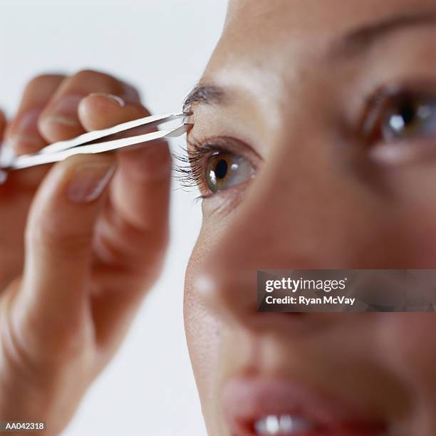 young woman plucking eyebrows - eyebrow tweezers imagens e fotografias de stock